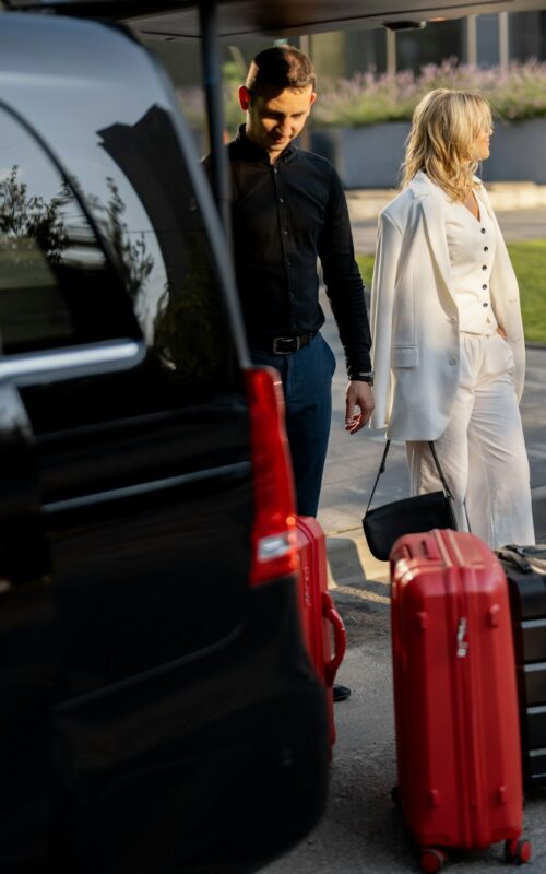 Business couple near minivan taxi with a suitcases and chauffeur
