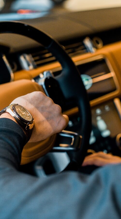 partial view of businessman checking watch in luxury car